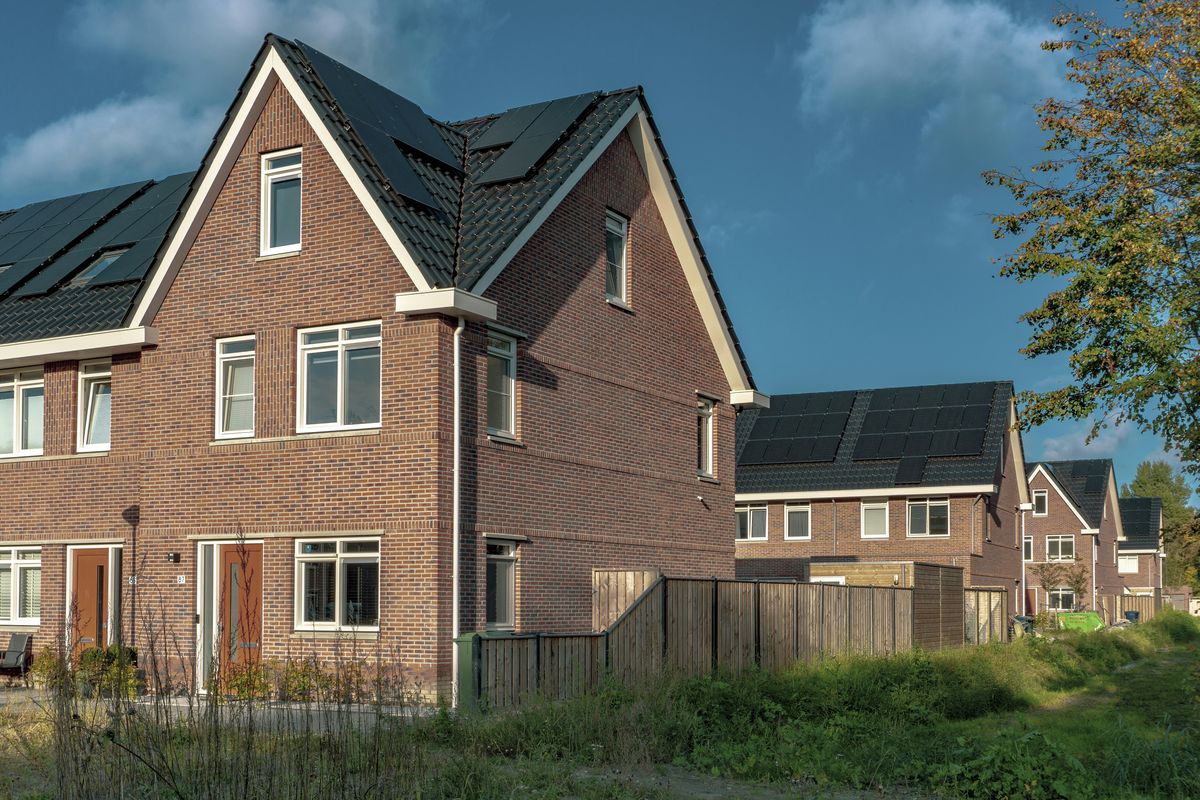 Nieuwe woningen in rode baksteen met zonnepanelen op het dak.