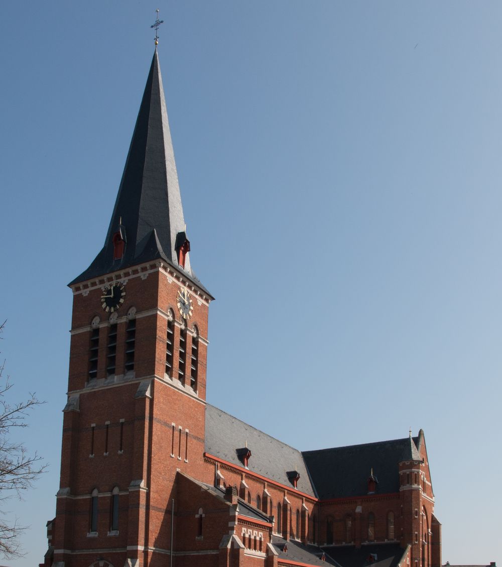 De bakstenen Sint-Niklaaskerk van Putte met haar hoge leien torenspits.